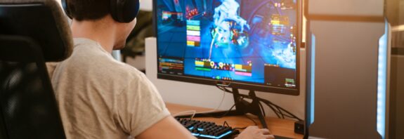 Spieler sitzt konzentriert vor Computer mit Headset | Inline Skates